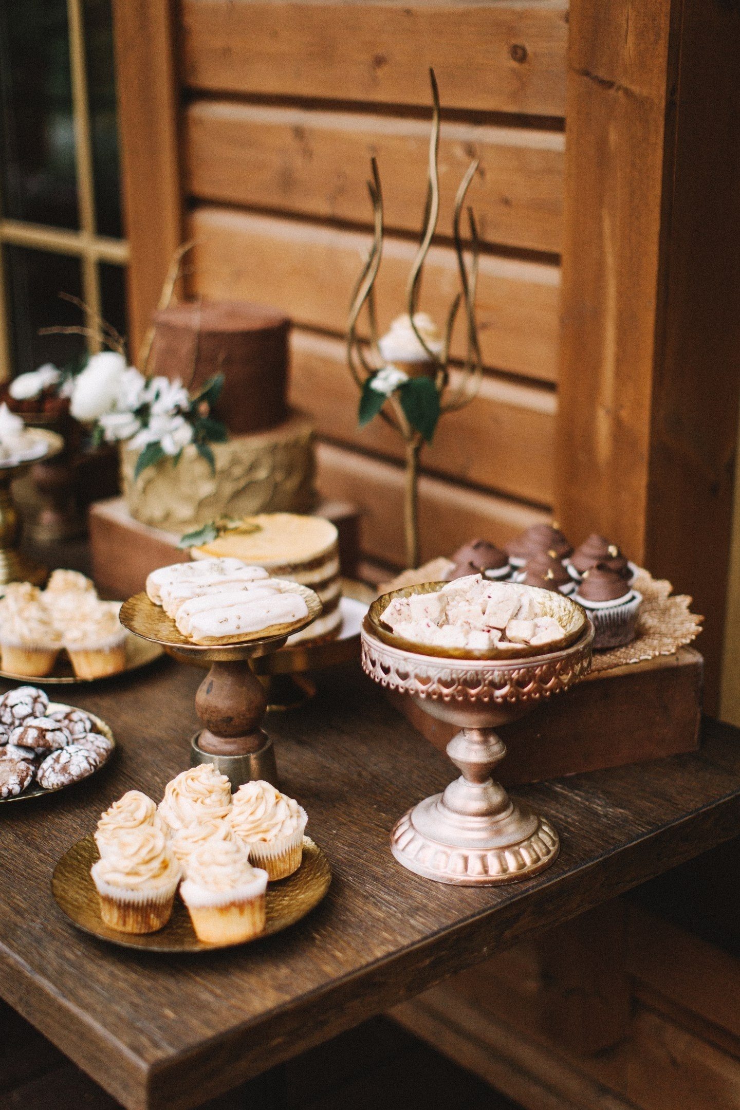 Gebrochene Schokoriegel, Trüffel, luftige Mokka-Desserts, dekoriert mit Kaffeebohnen und durchbrochenen Keksen mit Zuckerguss im Hochzeitsstil sehen in Gesellschaft von alten Kisten und kunstvollen Ständen großartig aus